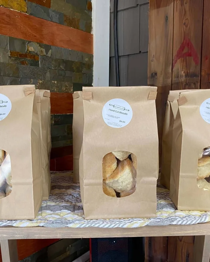 Three kraft bakery bags with window fronts on a bench