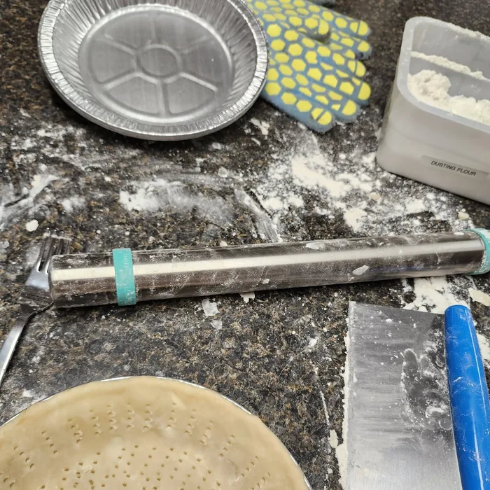 A pie tin, rolling pin and pastry mid-make on the counter