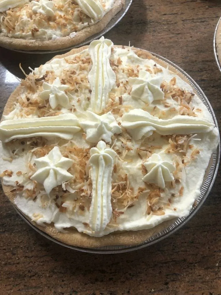 A whole coconut cream pie with piped cream and toasted coconut