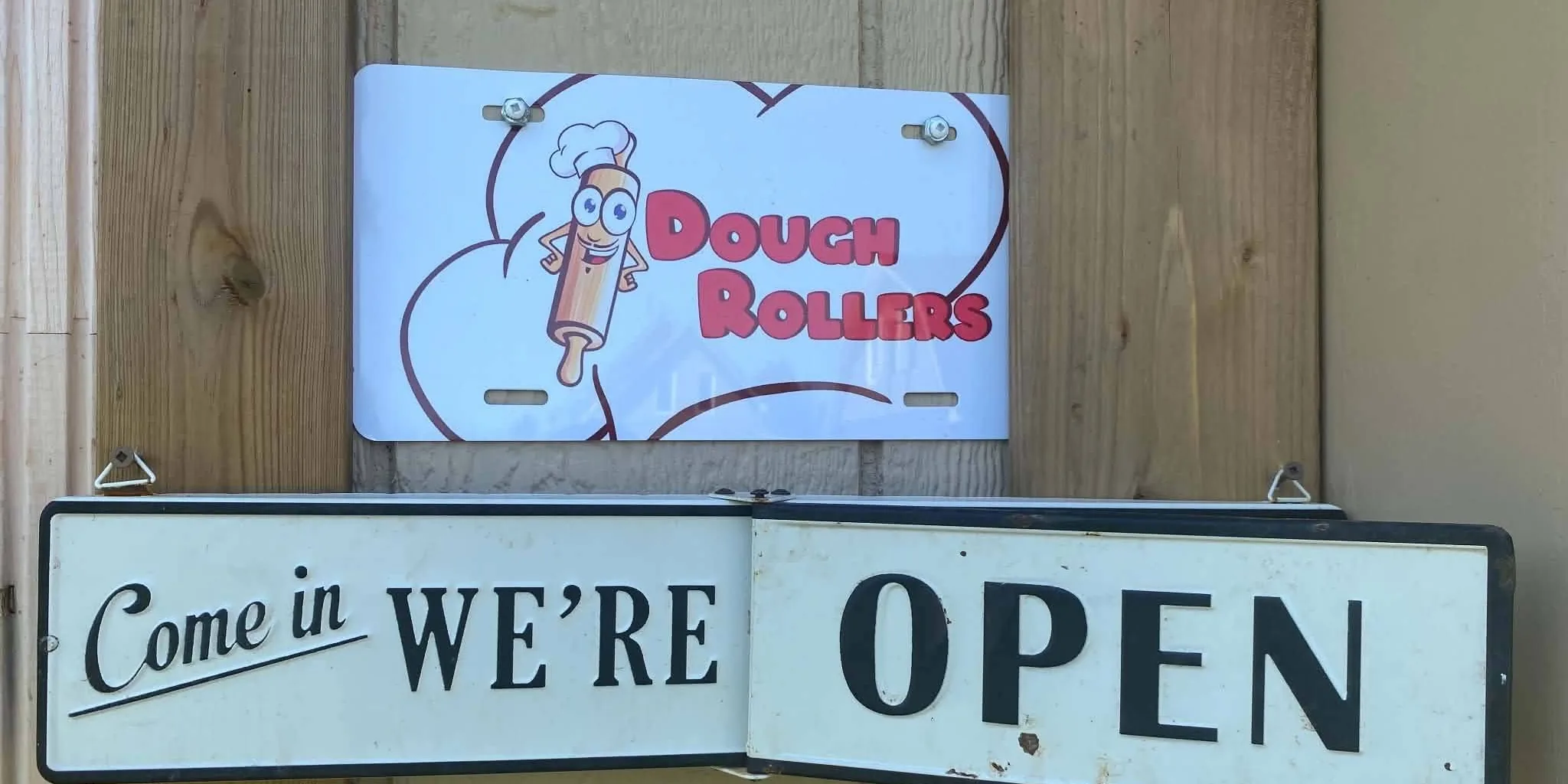 The Come in, WE'RE OPEN sign on barn board at the farm store door